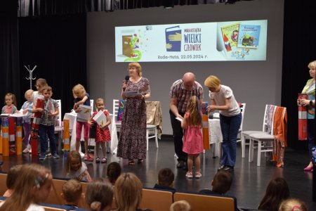 Dyrektorzy szkoły, biblioteki i przedszkola rozdają nagrody dzieciom
