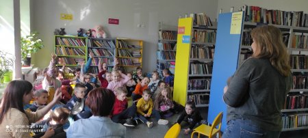 Bibliotekarka mówi do siedzących na dywanie dzieci