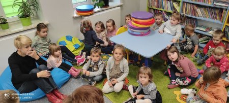 Przedszkolaki siedzą na dywanie w bibliotece