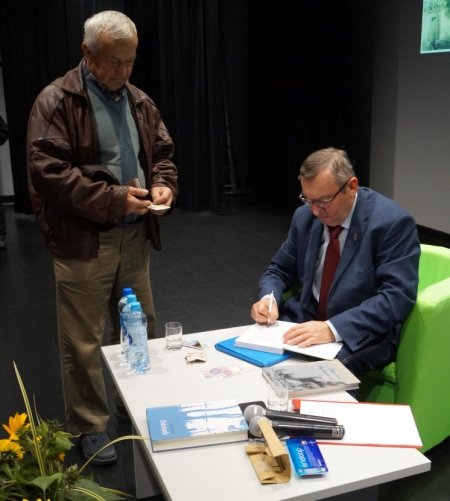 dr Leon Popek podpisuje książkę jednemu z uczestników spotkania