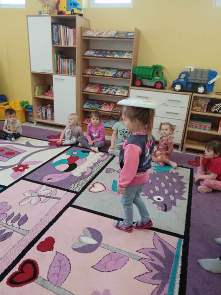 Dzieci chodzą z książką na głowie