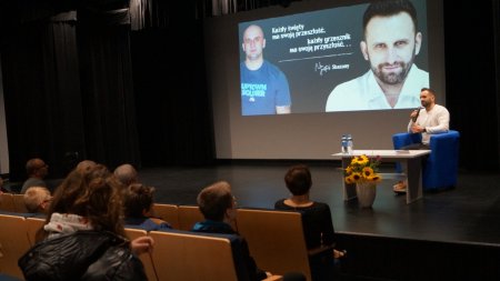 Na scenie siedzi autor Grzegorz Czerwicki, widać część widowni siedzącą tyłem