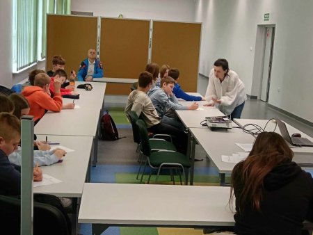 Prowadzące mówią do siedzących w ławkach uczestników