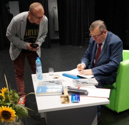 dr Leon Popek podpisuje książkę jednemu z uczestników spotkania