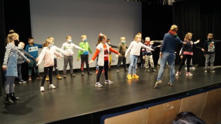 Na scenie uczniowie z prowadzącą, wspólnie ćwiczą baletowy układ choreograficzny