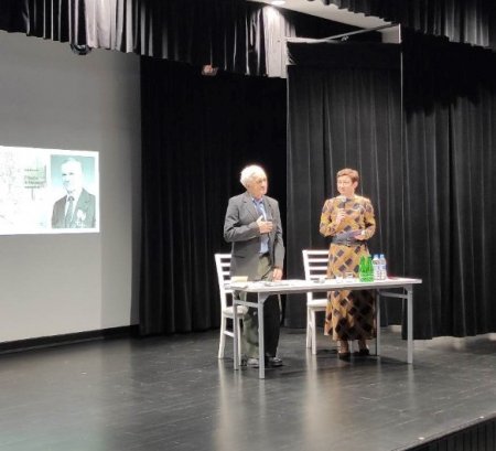 Na scenie stoi Tadeusz Borowski oraz prowadzaca spotkanie 