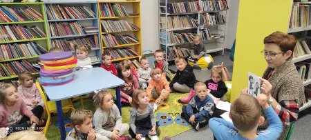 Bibliotekarka pokazuje dzieciom ilustrację a one ją oglądają