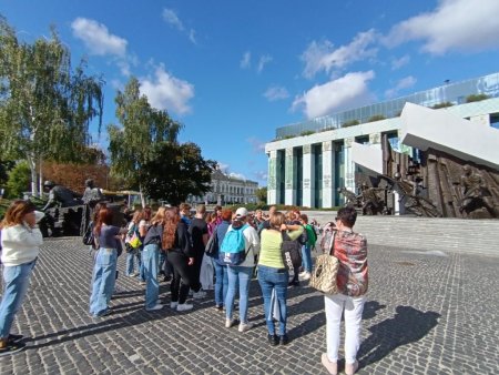 Grupa z przewodnikiem na placu przed pomnikiem powstańców warszawskich