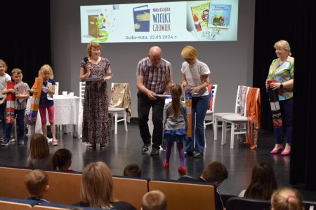Dyrektorzy szkoły, biblioteki i przedszkola rozdają nagrody dzieciom