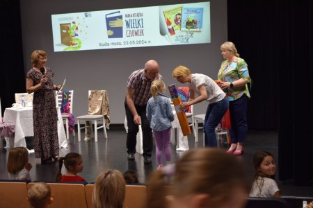 Dyrektorzy szkoły, biblioteki i przedszkola rozdają nagrody dzieciom