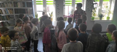 Dzieci stoją w grupie i słuchają bibliotekarki