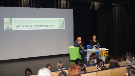 Widać częśc publiczności siedzącą tyłem oraz na scenie dr Leona Popka i prowadzącą 