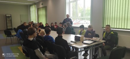 Prowadzący rozmawia z siedzącą przy stolikach młodzieżą