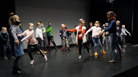 Na scenie uczniowie z prowadzącą, wspólnie ćwiczą baletowy układ choreograficzny