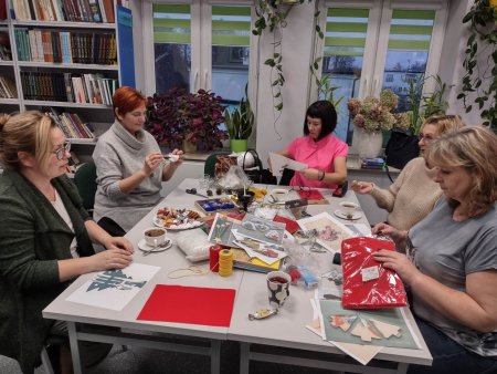 Przy stole siedzą członkinie DKK, na stole materiały do wykonywania ozdób świątecznych