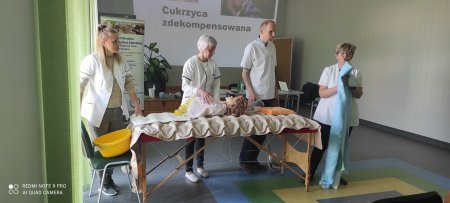 Uczniowie wraz z prowadzącą spotkanie prezentują na manekinie opieke nad osobą leżącą