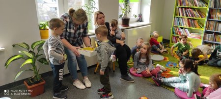 Dzieci podchodzą do bibliotekarki w losują domino