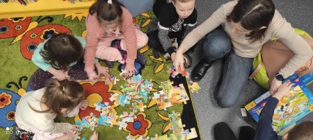 Dzieci układają puzle z nauczycielką