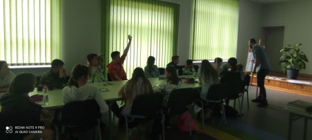 Uczestnicy siedzą przy stole i słuchają autora