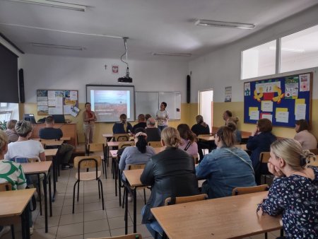 Prowadzące mówią do siedzących w ławkach rodziców