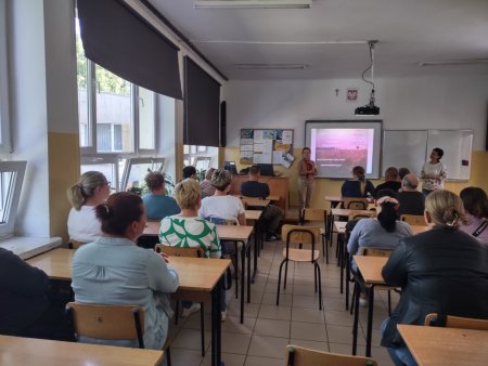 Prowadzące mówią do siedzących w ławkach rodziców