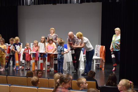 Dyrektorzy szkoły, biblioteki i przedszkola rozdają nagrody dzieciom