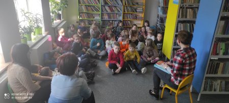 bibliotekarka czyta siedzącym na dywanie dzieciom